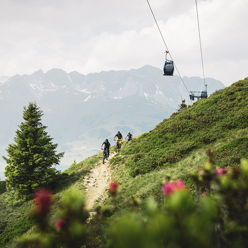 Wanderer auf Bergpfad bei St. Anton am Arlberg mit Seilbahn und Alpenpanorama